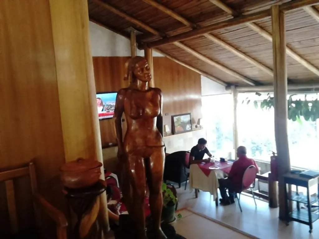 Interior del restaurante Los Manantiales con escultura en madera y comensales